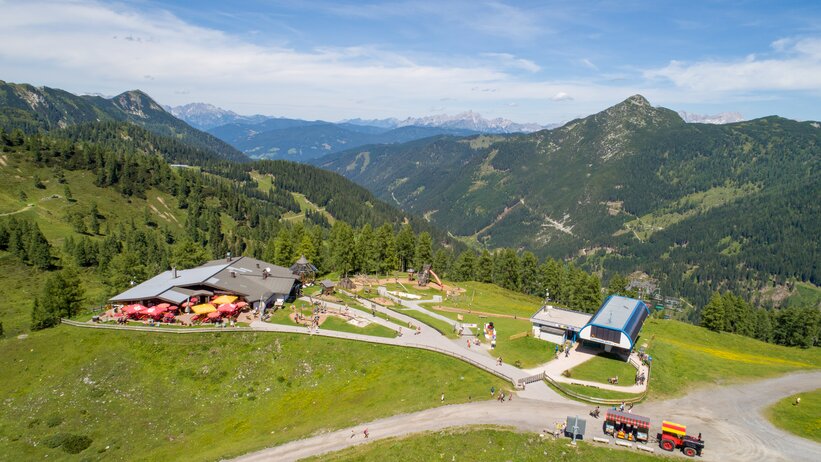 Sommerliche Aussicht auf Gamskogelhütte mit Spielplatz, Gondelstation und Bergen im Hintergrund | © Zauchensee Liftgesellschaft