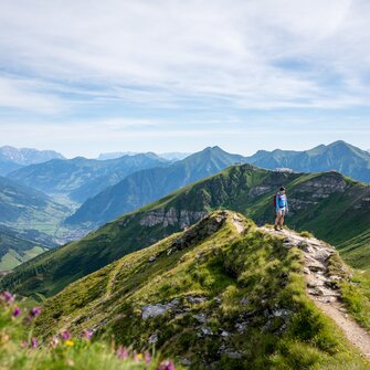Hiker on a ridge trail at Stubnerkogel with a wide view over the green Gastein Valley and the surrounding mountain peaks | © Gasteinertal Tourismus GmbH, Christoph Oberschneider