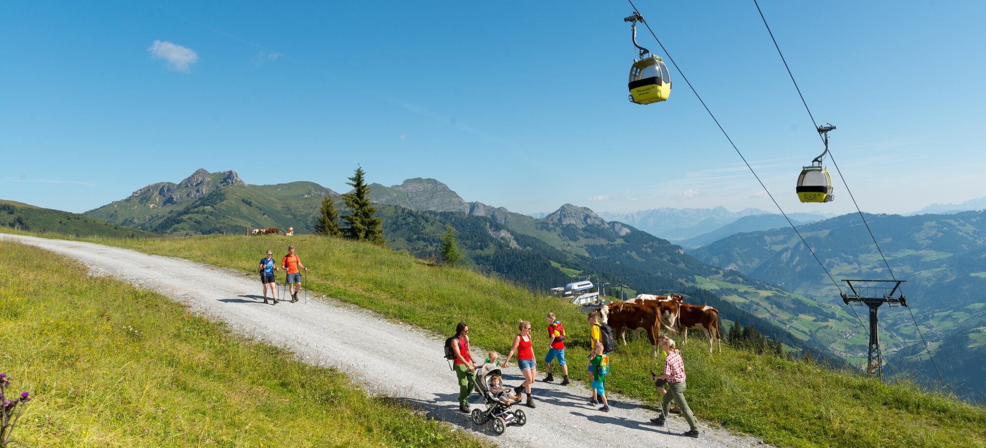 People walk up the mountain on a gravel road under a cable car | © Gruber Michael