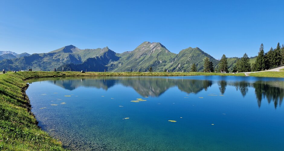 Lake Himmelreich with crystal-clear water, mountain reflections, green shore and deep blue sky on a summer day. | © TVB Großarltal