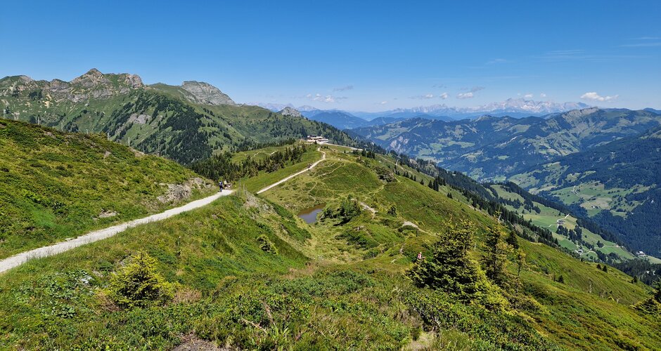 Panoramic hiking trail over green mountain ridges with valley view and blue sky, along the Himmelsroute near Kieserl. | © TVB Großarltal