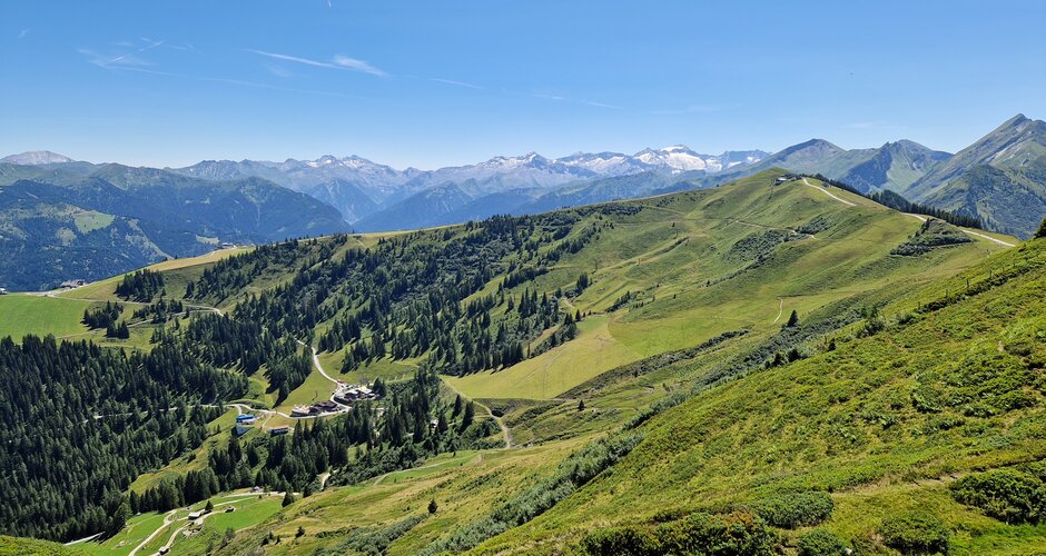 View from Kreuzkogel of green ridges, alpine paths and the wide Hohe Tauern panorama under a clear summer sky. | © TVB Großarltal