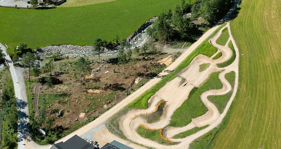 Aerial view of a mountain bike park with winding dirt trails in a green landscape | © Sport Panorama