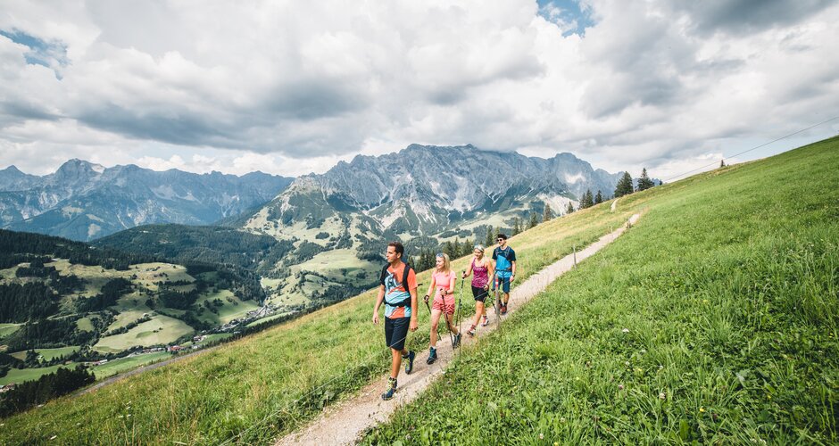 Five hikers walk along mountain path above green valley with panoramic view of the rugged Hochkönig massif in the background | © Hochkönig Tourismus GmbH