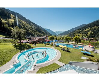 Außenpool des Solarbads Dorfgastein mit Blick auf grüne Berge und Liegewiese. | © Gasteinertal Tourismus GmbH