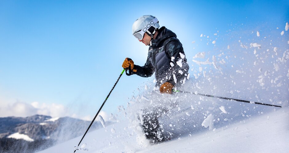 Skier skis through deep snow and the snow flies sideways into the air