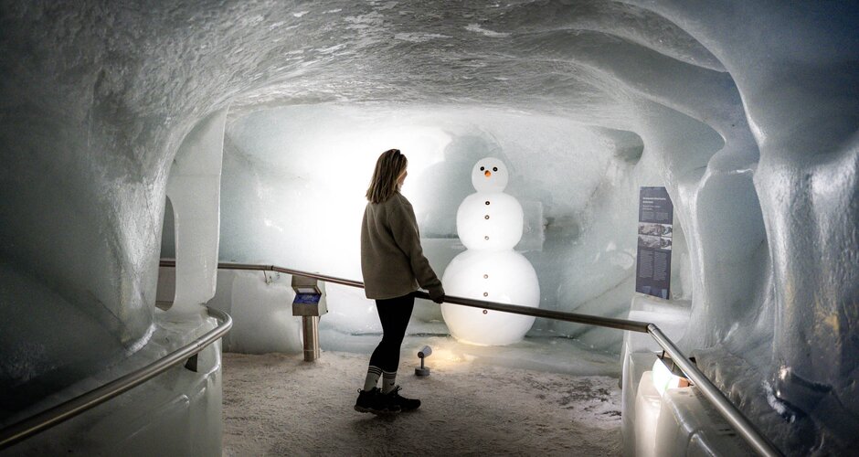 Visitor looking at an ice snowman in Dachstein Ice Palace, surrounded by ice walls. | © Juris Adventure