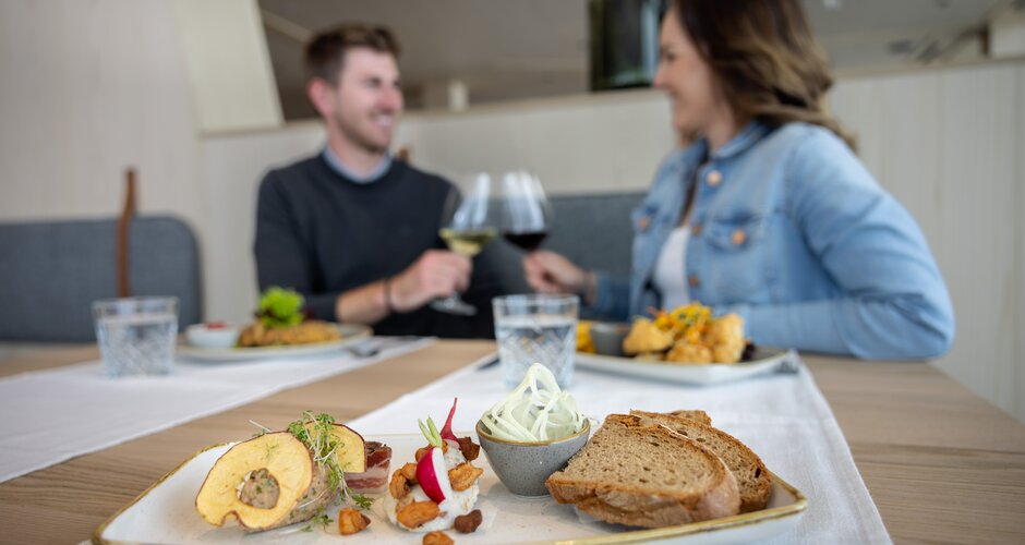 Couple enjoying regional dishes at the Dachstein glacier restaurant with wine and bread. | © Harald Steiner
