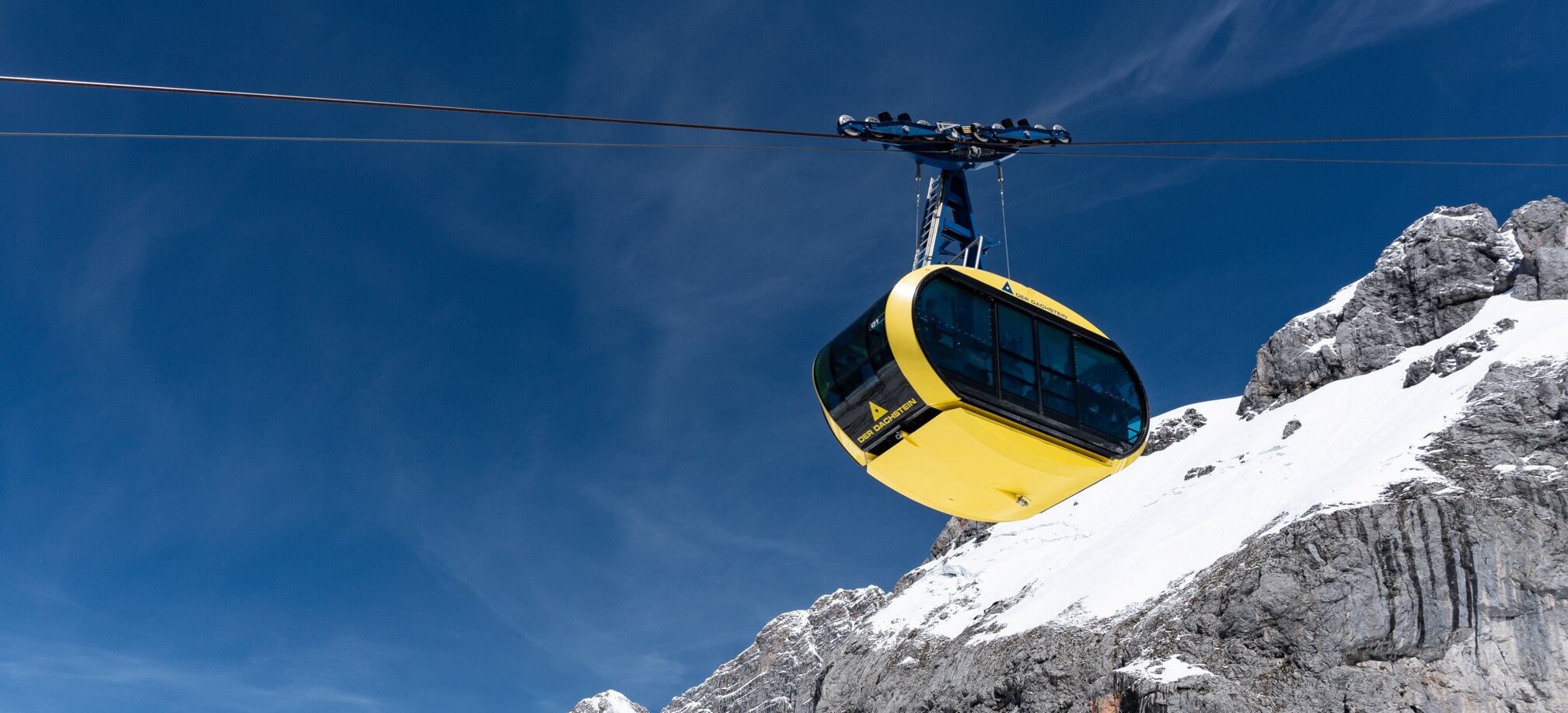 Yellow gondola traveling over snowy mountain landscape at Dachstein glacier. | © Josh Absenger