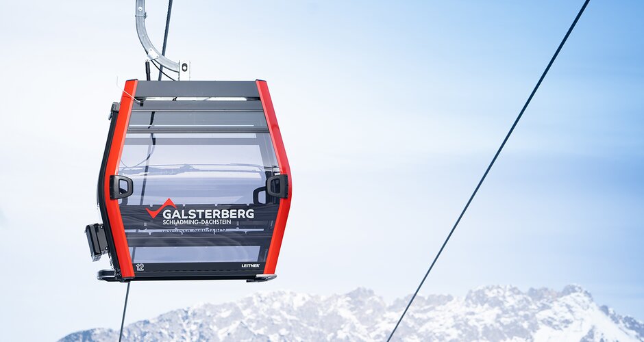 Red Galsterberg gondola with snowy mountains in the background. | © Josh Absenger