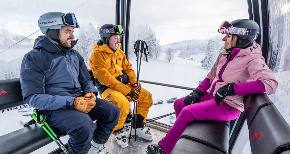 Three skiers laughing in the gondola on a winter ride at Galsterberg. | © Mirja Geh