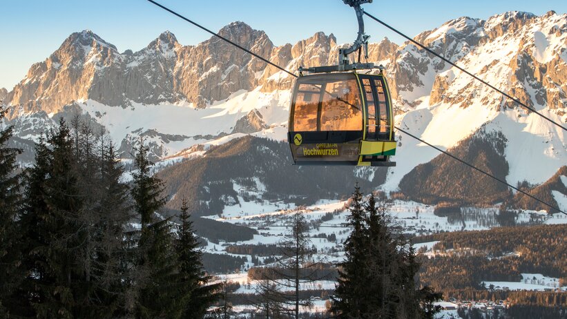 Yellow Hochwurzen gondola floats in front of snow-covered mountains at sunset. | © Alexander Klünsner