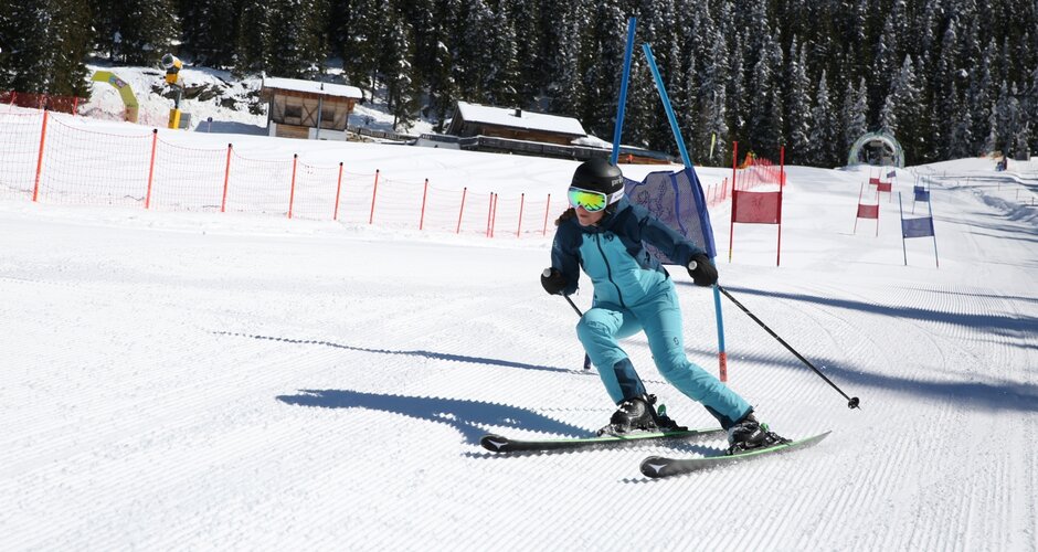Skier in a blue suit navigates a slalom course on Planai, closely passing a gate. | © Herbert Raffalt