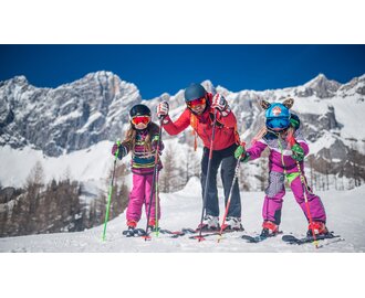 Familie mit zwei Kindern beim Skifahren vor schneebedeckter Bergkulisse. | © Christine Höflehner