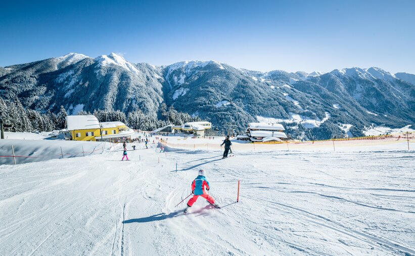 Child on skis skiing down the slope between short slalom poles and further down more children can be seen | © Markus Rohrbacher
