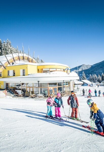 A small group of children are standing on the slope and a yellow building can be seen in the background | © Markus Rohrbacher