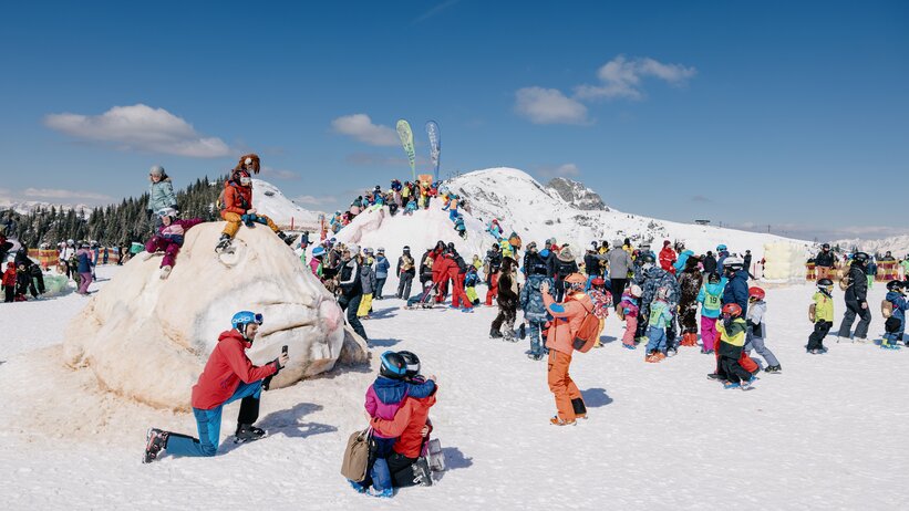 Many people in ski clothing stand around a bunny statue made of snow | © Markus Rohrbacher