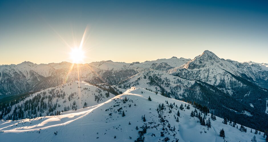 Snowy mountain landscape at sunset with trees and mountains in the background | © Markus Rohrbacher