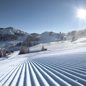 Perfekt präparierte Skipisten im Skigebiet Alpendorf mit Sonne, Schnee und Bergen