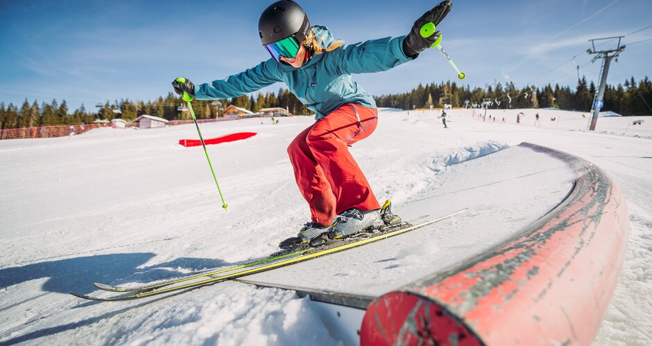 A girl skis over an action obstacle.