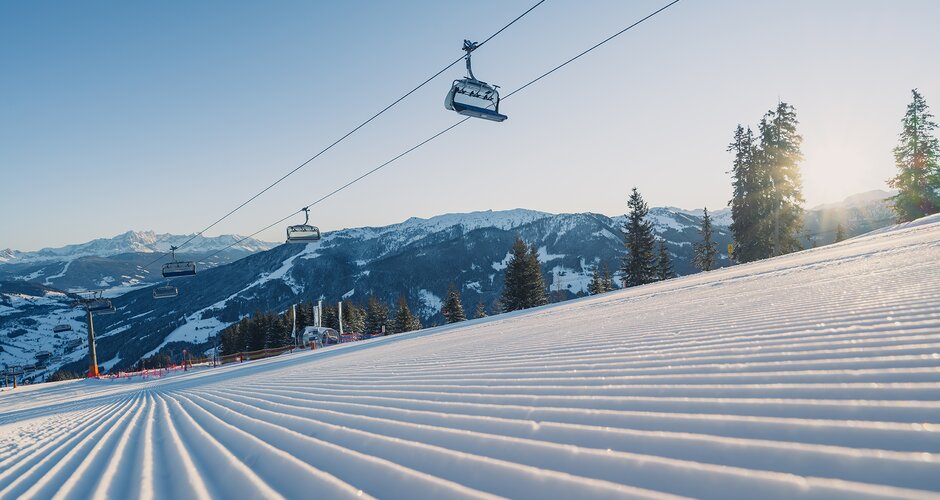 Perfectly groomed ski slope in the morning with chairlift and mountains in background | © Snow Space Salzburg
