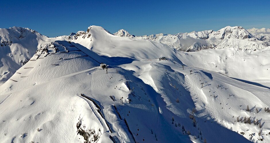 Panoramic view from Gamskogel with ski slopes, lifts and snowy mountains in background