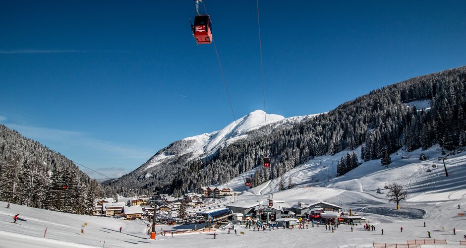 Skiarena mit Gondeln, Pisten, verschneiten Bergen und Skifahrern in Zauchensee