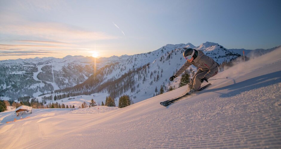 Skier carving at sunrise in Zauchensee with fresh snow and mountain panorama