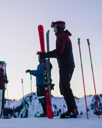 Vier Skifahrer stehen auf einem verschneiten Hang unter einem violetten Himmel. | © Ski amadé