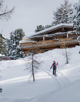 Ski tourer approaches Graukogelhütte on snowy slope through forested winter landscape | © Gasteinertal Tourismus GmbH, Christoph Oberschneider