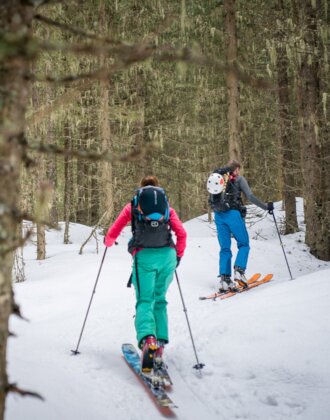 Two ski tourers ascend through mossy, snowy forest with scattered trees and white ground | © Gasteinertal Tourismus GmbH, Christoph Oberschneider