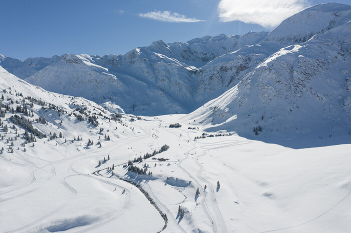 Expansive cross-country ski trails wind through the snowy valley of Sportgastein, surrounded by towering mountain peaks. | © Gasteinertal Tourismus GmbH, Christoph Oberschneider