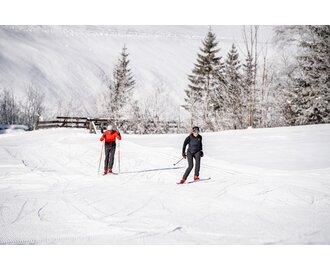 Two cross-country skiers on groomed trail in Grossarltal with snowy fields trees and winter landscape | © Gipfelfieber