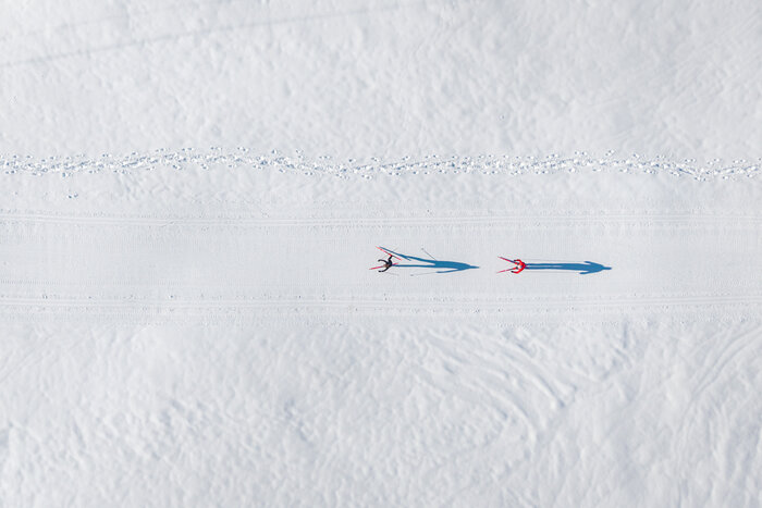 Two cross-country skiers glide along groomed trail in Grossarltal across wide snowy winter landscape | © Gipfelfieber