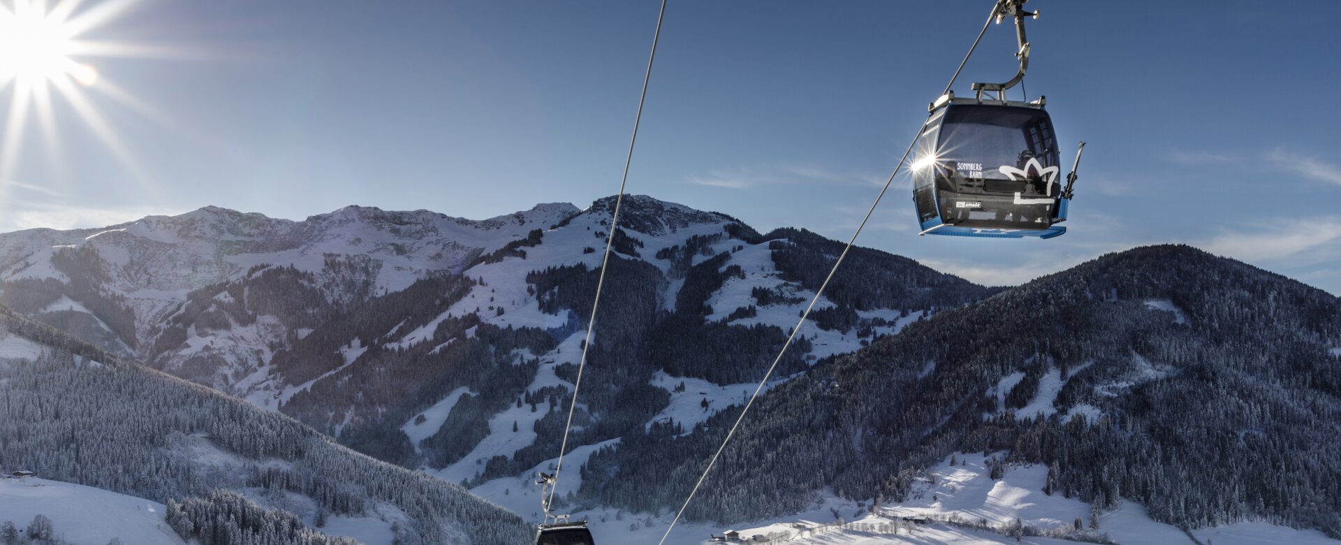Gondeln der Sonnbergbahn fahren über verschneite Hänge bei Maria Alm in der Wintersonne | © www.felsch-foto.at