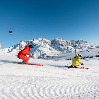 Zwei Skifahrer auf frisch präparierter Piste mit Blick auf das verschneite Hochkönig-Massiv | © Hochkönig Tourismus GmbH