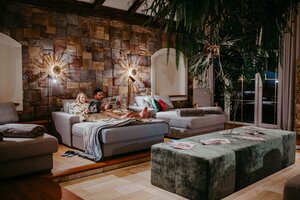 Mann und Kind lesen im Spa auf Liege vor Steinwand und großen Hängepflanzen | © Nadja Jabli