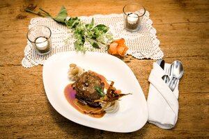 Hauptgang mit Fleisch, Sauce und Püree auf weißem Teller mit Tischdeko