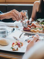 Menschen teilen sich eine Platte mit Fleisch, Salat und Brot im Hotelrestaurant