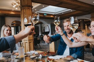 Gruppe stößt mit Weiß- und Rotwein im Restaurant des Hotel Tauernhof an