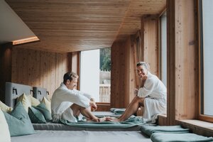Paar in Bademänteln im Ruheraum mit Holzdesign im Hotel Tauernhof