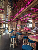 Rustikale Alpenbar mit Holzbalken, pink beleuchteter Decke, Barhockern, Whirlpool und Metallbär