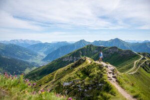 Wanderer auf einem Gratweg am Stubnerkogel mit weitem Blick über das grüne Gasteinertal und die umliegenden Berggipfel | © Gasteinertal Tourismus GmbH, Christoph Oberschneider