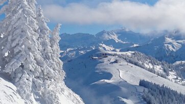 View of a chairlift mountain station and a ski slope framed by a deep snow-covered mountain landscape