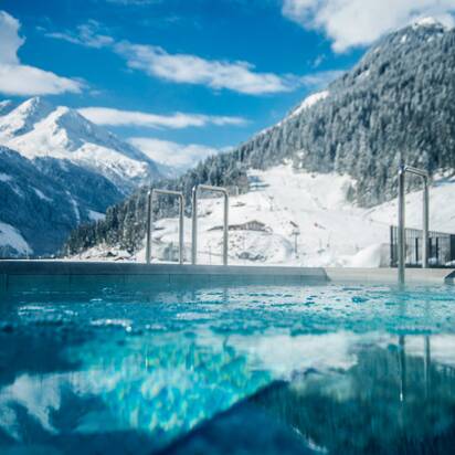 Schwimmbecken mit bergiger Schneelandschaft im Hintergrund | © Max Steinbauer Photography