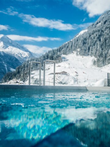 Swimming pool with mountainous snowy landscape in the background | © Max Steinbauer Photography