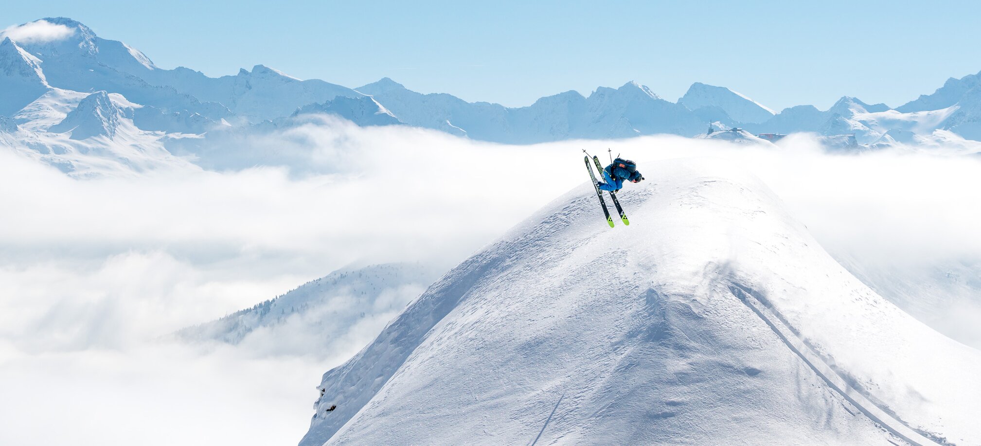 Skifahrer mach einen Backflip über eine Schneekuppel und rundherum sind verschneite Berge und ein blauer Himmel zu sehen | © Gasteinertal Tourismus GmbH, www.oberschneider