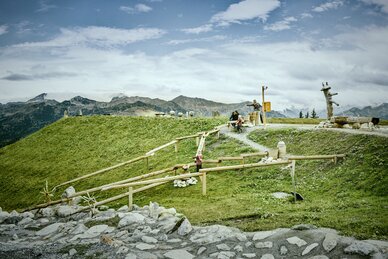 Kinder spielen an Wasserstationen auf Erlebnisweg im Großarltal mit Holzrinnen, Wiese und Bergpanorama | © Chris Rogl