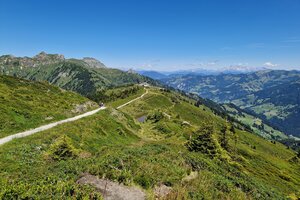 Panoramic hiking trail over green mountain ridges with valley view and blue sky, along the Himmelsroute near Kieserl. | © TVB Großarltal