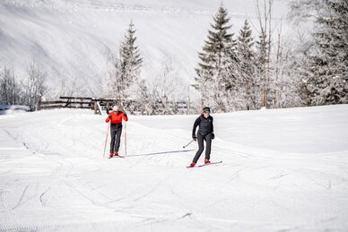 Two cross-country skiers on groomed trail in Grossarltal with snowy fields trees and winter landscape | © Gipfelfieber